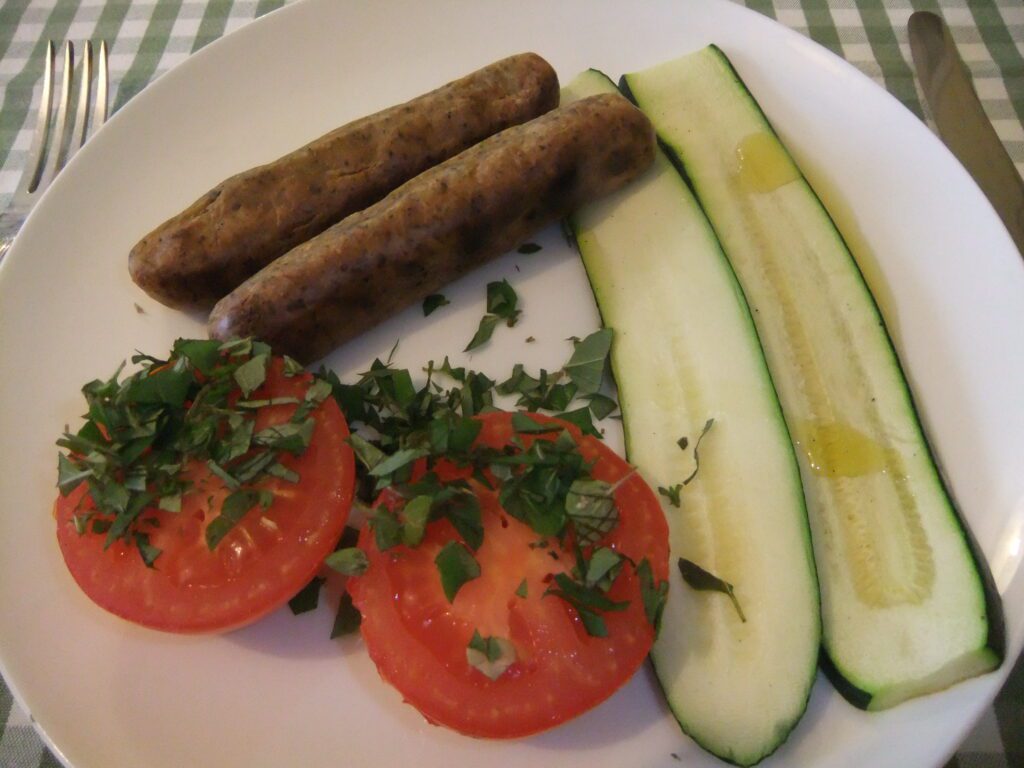 Baked herby sausages with courgette and tomato
